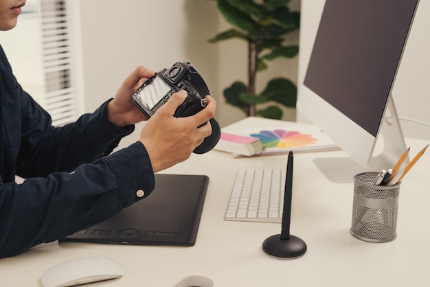 Arbeitsplatz des Fotografen. Kreative Designerhände arbeiten mit Grafiktablett, Fotoausrüstung auf dem Tisch