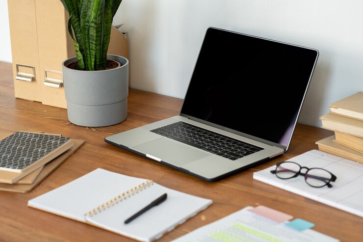 Foto arbeitsplatz des home-office-mitarbeiters mit laptop, brille, offenem notizbuch mit stift und anderem zubehör auf holztisch