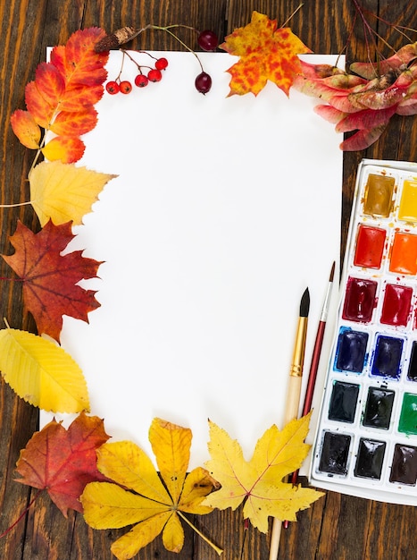 Arbeitsplatz des Künstlers Blatt Papier malt Pinsel und Blätter im Herbst Herbstkonzept Ansicht von oben