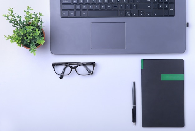 Arbeitsplatz im Büro mit Laptop, Notebook, Brille und anderen Geräten.