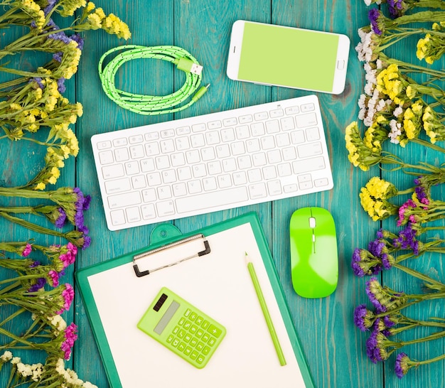 Arbeitsplatz mit drahtloser, schlanker Tastatur, grüner Maus, Smartphone-Zwischenablage-Rechner