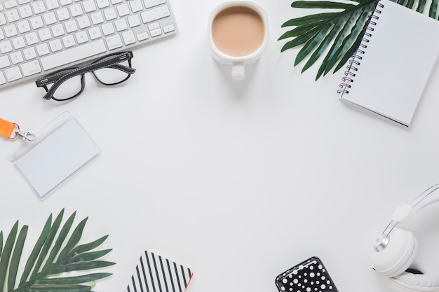 Foto arbeitsplatz mit geräten, kaffeetasse und gläsern nahe palmen