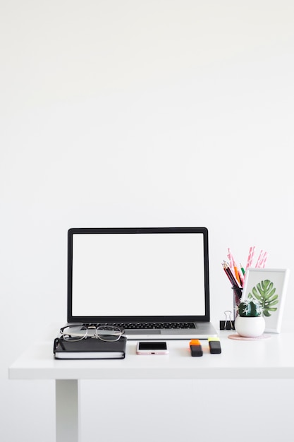 Foto arbeitsplatz mit laptop in der nähe von brillen, notizbuch, markierungen und handy