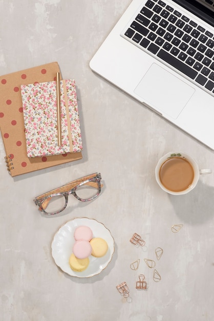 Arbeitsplatz mit Laptop, Notebook, Brille, Tasse Kaffee und Lisianthus-Blumen auf Grau