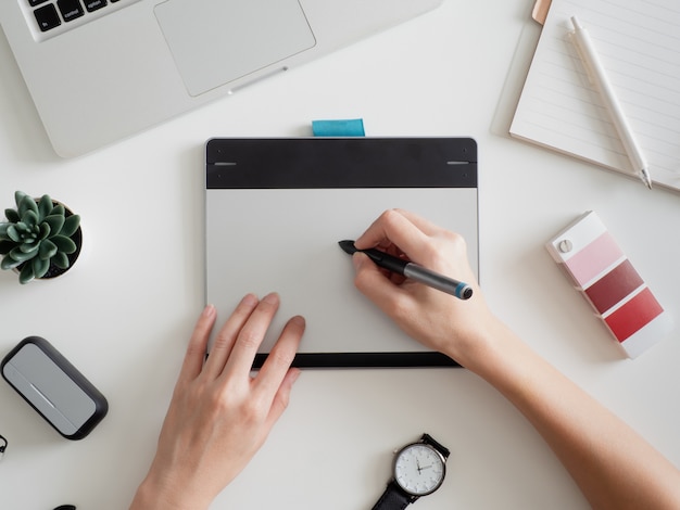 Arbeitsplatz mit Laptop, Notebook, Grafiktablett und Smartphone.