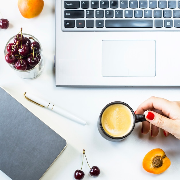 Arbeitsplatz mit Laptop und Notizbuch auf einer weißen Tabelle mit Beeren- und Fruchtsnack