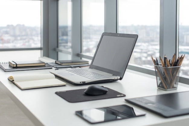 Arbeitsplatz mit Notebook-Laptop Bequemer Arbeitstisch in Bürofenstern und Blick auf die Stadt.