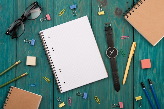 Arbeitsplatz mit Notizblock-Brillenuhr und anderem Büromaterial auf einem Schreibtisch