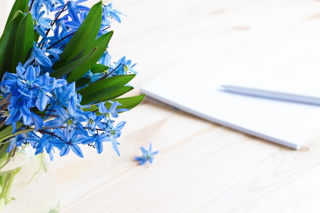 Foto arbeitsplatz tisch und notizbuch mit weißem papier und stift konzentrieren sich auf eine vase mit blauen blumen