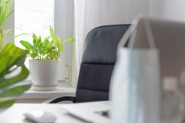 Arbeitsplatz zu Hause am Fenster mit einer Laptop-Schutzmaske und einem Desinfektionskonzept der Quarantäne während der weltweiten Coronavirus-Pandemie