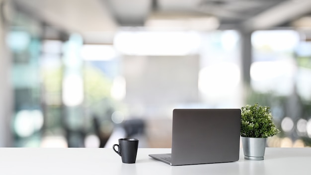 Arbeitsplatzlaptop-Computer und Kaffeetasse mit Blumentopf auf Bürotisch.