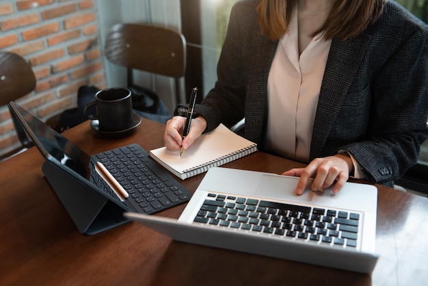 Arbeitsprozess im modernen Büro Young Woman Account Manager, der am Tisch mit neuen Geschäftsprojekten arbeitet, Tastatur mit zeitgemäßem Laptop eingeben