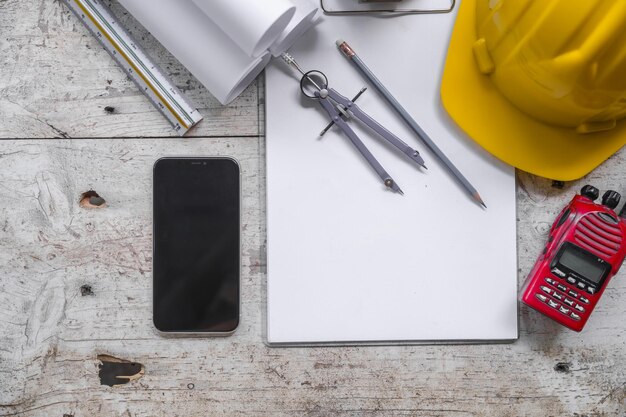 Arbeitsumgebung mit einem Laptop, einem gelben Hardhat-Rechner, einem Schraubendreher und einem klappbaren Lineal auf einem