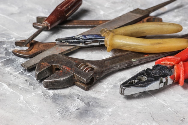 Arbeitswerkzeug auf grauem Betonhintergrund. Hammer, Zange, Feile, Schraubenschlüssel, Schraubendreher.