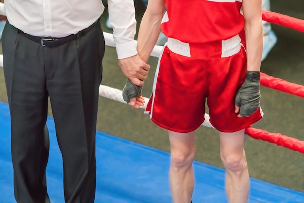 Árbitro y boxeador en uniforme rojo en el ring.