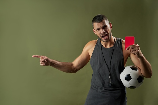 Foto Árbitro de futebol zangado em roupas esportivas cinza segurando um cartão vermelho no braço isolado sobre fundo verde