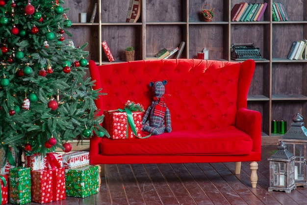 árbol de año nuevo con decoración sofá rojo estantería cajas presentes