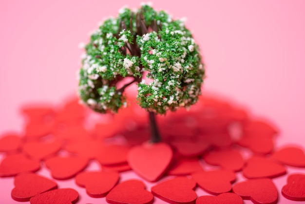 Árbol artificial y corazones sobre un fondo rosa.
