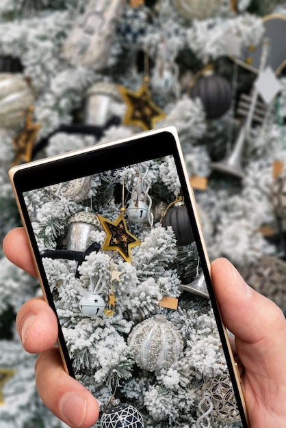 El árbol blanco cubierto de nieve en la pantalla del teléfono inteligente.