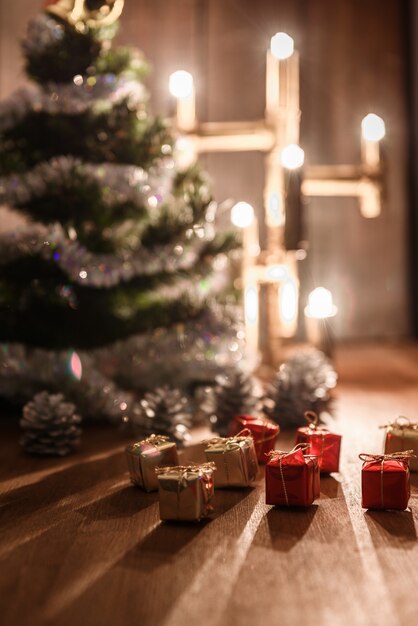 El árbol decorativo de Navidad está adornado con soportes de lluvia sobre la mesa con una lámpara encendida.