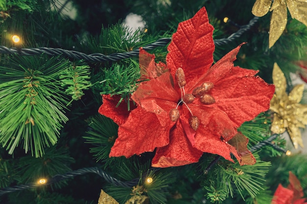 Foto Árbol de navidad artificial y flor de flor de pascua roja.
