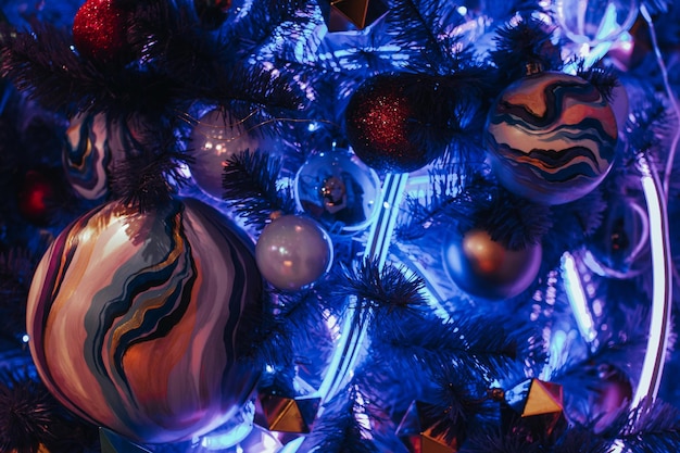 Foto Árbol de navidad azul neón creativo decorado con bola de navidad pintada a mano y guirnalda de neón