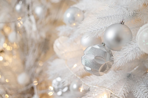 Un árbol de Navidad blanco está decorado con juguetes de plástico plateado Decoración festiva brillante para el nuevo año