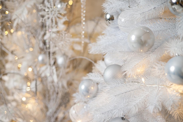 Un árbol de Navidad blanco está decorado con juguetes de plástico plateado Decoración festiva brillante para el nuevo año