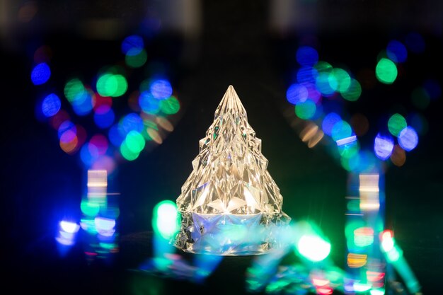 un árbol de Navidad brillante como el cristal se encuentra detrás de dos copas de vino borrosas y rodeadas por una guirnalda brillante. primer plano, enfoque suave ...