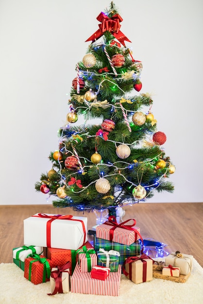 El árbol de navidad con cajas de regalo en el suelo.