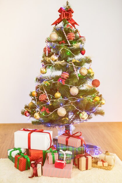 El árbol de navidad con cajas de regalo en el suelo.