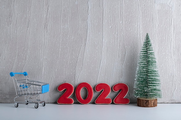 Foto Árbol de navidad, carro y números 2022 sobre fondo claro. compras para el año nuevo. copia espacio