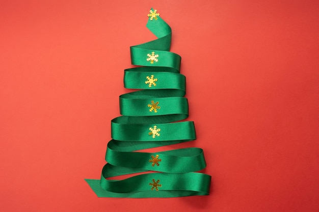 Árbol de Navidad de cinta de cinta verde sobre fondo rojo.