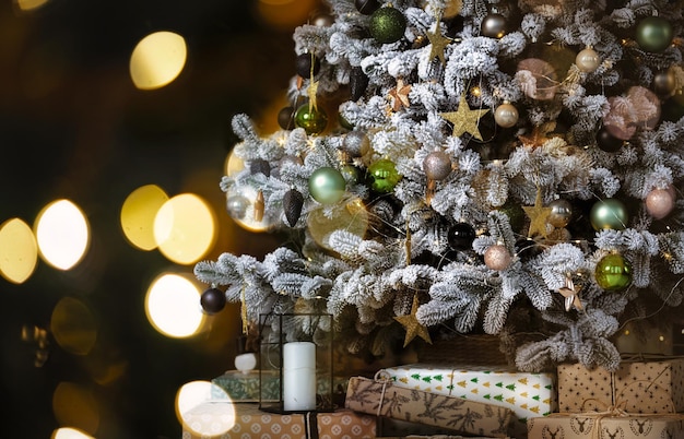 Árbol de Navidad con decoración diferente y muchos regalos sobre fondo borroso con luces brillantes