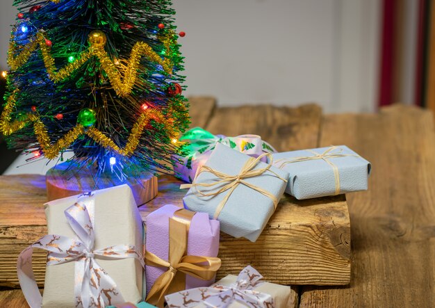 Árbol de Navidad con decoración y regalos sobre un fondo blanco de madera