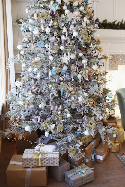Foto Árbol de navidad decorado con adornos navideños y regalos.