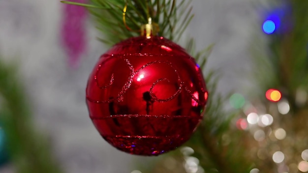 Árbol de navidad decorado con bola de cristal rojo en la rama de abeto de navidad en el fondo bokeh de guirnaldas de bombillas parpadeantes