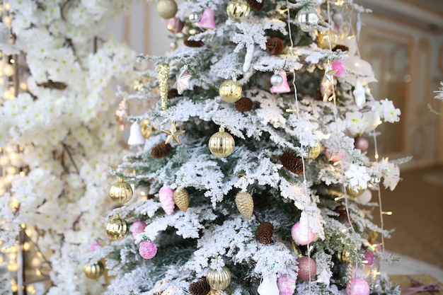 Foto Árbol de navidad decorado con bolas de oro y rosa con juguetes y primeros planos de nieve decorativa