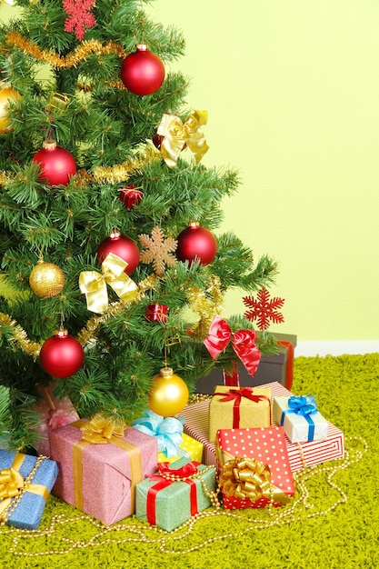 Foto Árbol de navidad decorado con regalos sobre fondo de pared verde