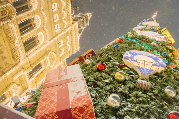 Árbol de navidad gigante decorado con bolas de colores y regalos durante las nevadas