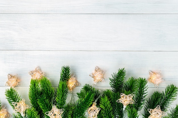 Foto Árbol de navidad con guirnaldas de luces en la parte inferior del fondo de madera blanca. feliz navidad y feliz año nuevo telón de fondo, vista superior. borde hermoso marco en blanco con espacio de copia.