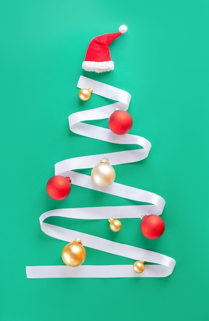 Árbol de Navidad hecho de cinta con bolas de Navidad sombrero de Papá Noel en fondo verde vacaciones creativas