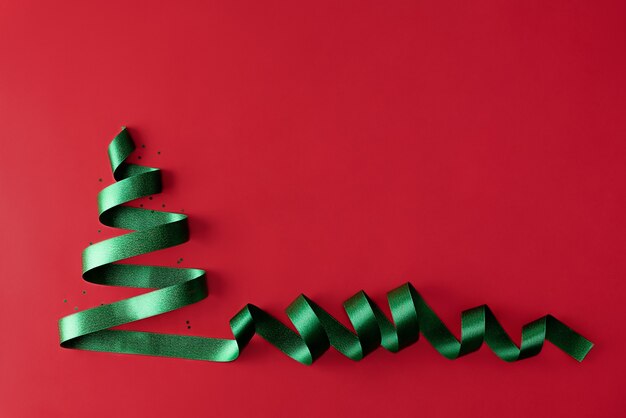 Foto Árbol de navidad hecho de cinta verde sobre un fondo rojo tarjeta de felicitación de navidad