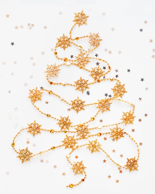 Foto Árbol de navidad hecho de guirnalda de copo de nieve dorado con confeti de estrellas plateadas.