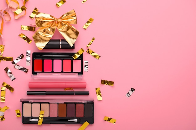 Foto Árbol de navidad hecho de productos de maquillaje en una vista superior de fondo rosa. productos de belleza cosmética para navidad, lápiz labial, paleta de sombras, brillo de labios, delineador de ojos. concepto de regalo de vacaciones para una mujer. copie el espacio.