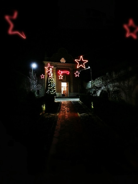 Foto Árbol de navidad iluminado y casa por la noche