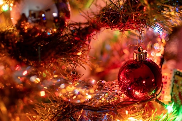 Un árbol de Navidad de juguete en forma de bola roja de Navidad cuelga de una rama de abeto rodeado de adornos de Año Nuevo