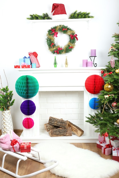 Foto Árbol de navidad junto a la chimenea en la habitación