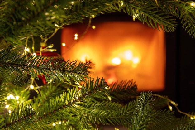 El árbol de navidad y las luces cierran el fondo de la chimenea ardiente