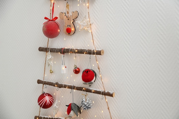 Foto Árbol de navidad de madera artesanal con juguetes colgados en la pared